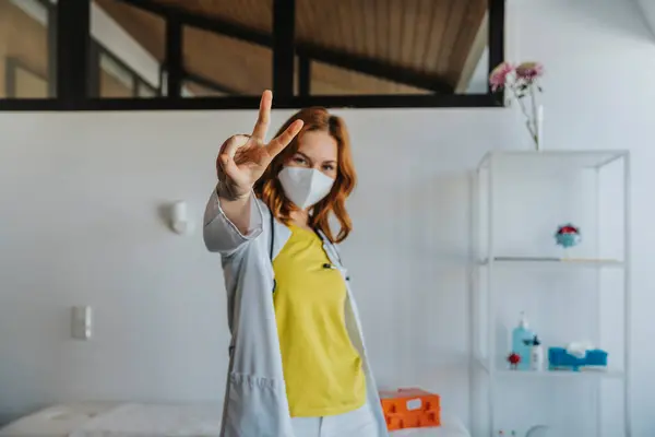 Læge Iført Beskyttende Ansigtsmaske Strækker Hånd Mens Gesturing Fred Tegn - Stock-foto