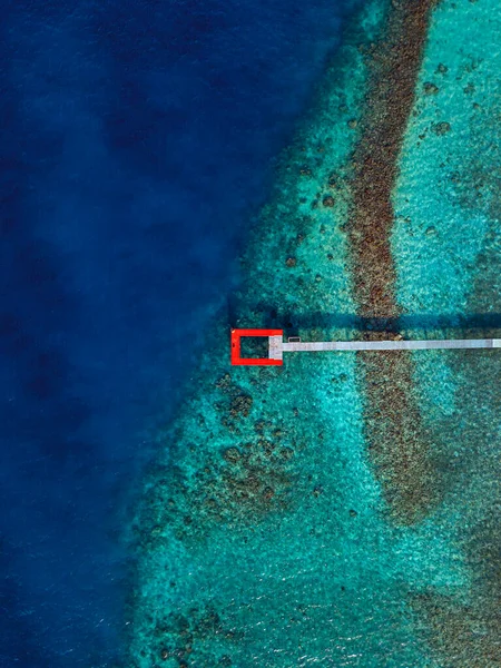 モルディブのカアフ環礁のThulusdhoo島のターコイズブルーの海の上の赤い桟橋 — ストック写真