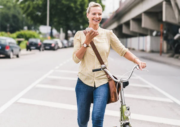 Smiling Businesswoman Wheeling Bicycle While Talking Smart Phone — Stock Photo, Image