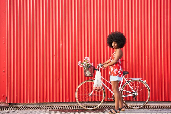 Kırmızı Kıvrımlı Duvarın Yanında Duran Bisikletli Afro Kadın — Stok fotoğraf