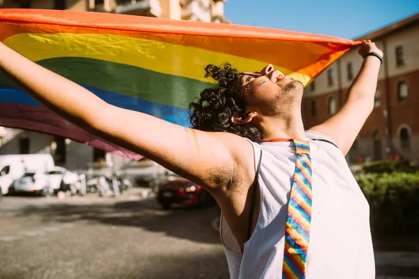 若い男性活動家が通りに虹の旗を持ちながら見上げ — ストック写真