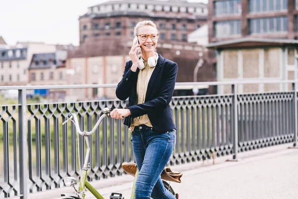 Sorrindo Mulher Viajante Bicicleta Rodas Enquanto Fala Telefone Celular Cidade — Fotografia de Stock