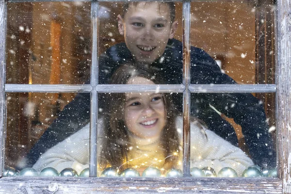 Smiling Siblings Looking Snowfall Window While Sitting Home — Stock Photo, Image