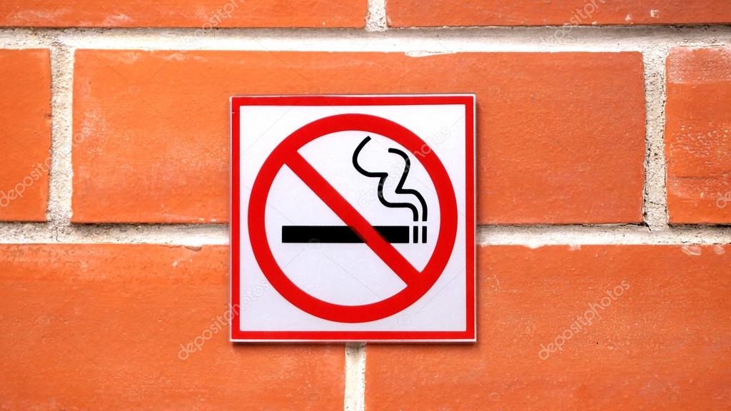 Sign hangs on a brick wall warning that smoking is not permitted in the area