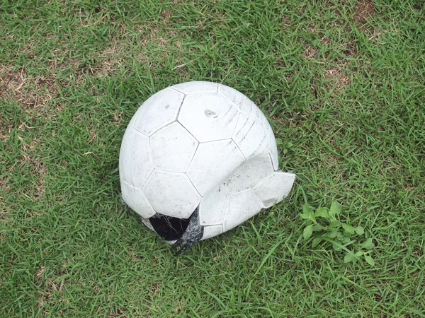 Çimenlerin üzerinde kırık futbol topu — Stok fotoğraf