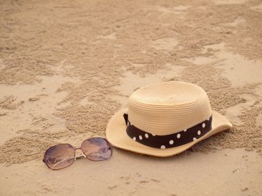 Tropik bir plajda hasır şapka ve güneş gözlüğü.