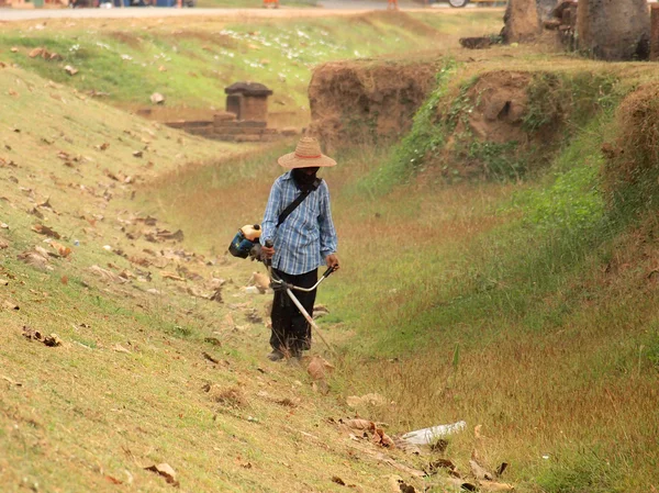 Cortador de grama trabalhador cortar grama no campo verde — Fotografia de Stock