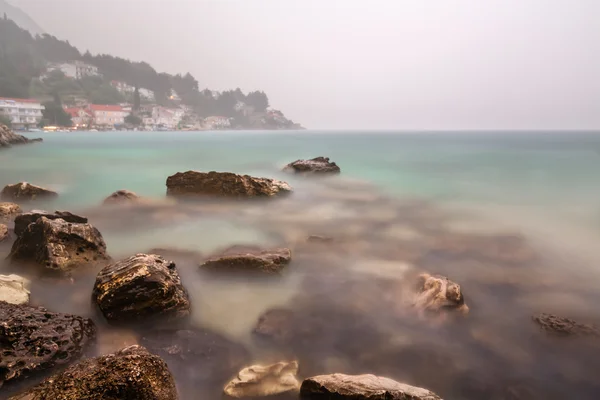 Nagy felhőszakadás és a köd, a sziklás strand közeli omis, Dalmácia, croa — Stock Fotó