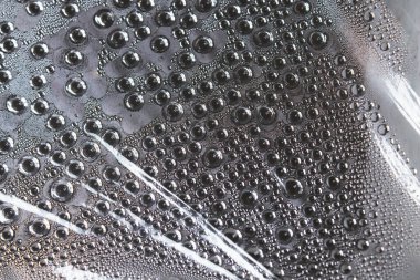 Filmdeki su damlacıkları. Şeffaf bir yüzeyde nem buharlaşması. Damlalar filme tutunuyor. Bir serada buharlaşma.