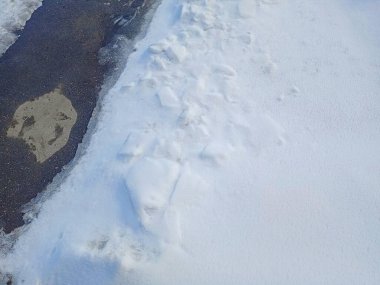 Kar erir ve asfalt ortaya çıkar. Toprak karın altından çıkar. Beyaz kar ve kara toprak.