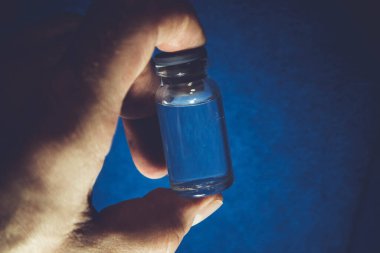 Tüp bebek aşısı. Mavi arka planda küçük bir şişede ilaç. Hastalık için antibiyotik şişesi. Hastalık ve virüsü tedavi etmek için aşı. Şırınga ve aşı.