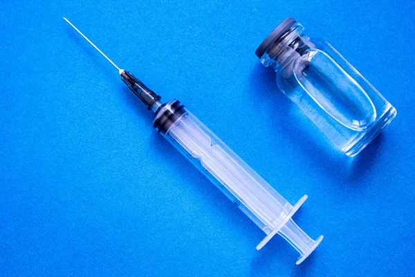 Antidote and syringe. Vaccine for animals in an ampoule on a blue background. Treatment and vaccination.