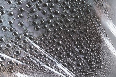 Filmdeki su damlacıkları. Şeffaf bir yüzeyde nem buharlaşması. Damlalar filme tutunuyor. Bir serada buharlaşma.