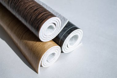 Muşamba. Beyaz arka planda üç rulo muşamba. Ev kullanımı için zemin kaplamaları. Tahta şeklinde muşamba tasarımı.