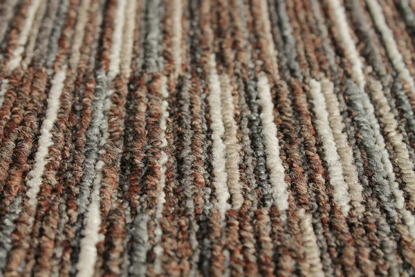 Texture of carpet floor close-up. Brown carpet with a pattern. Geometric shapes on the carpet.