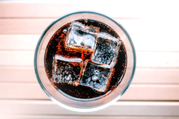A glass of soda with ice cubes. Chilled drink in a glass.