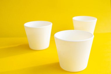Sarı arka planda beyaz tencereler boş. Masadaki boş kavanozlar. Çiçekler için konteyner.
