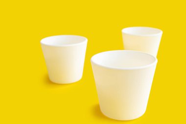 Sarı arka planda beyaz tencereler boş. Boş kavanozlar masaya..