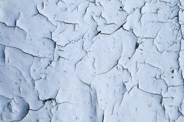 Boya çatladı ve düştü. Beyaz boya parça parça asılır. Boyalı yüzeyde çatlaklar.