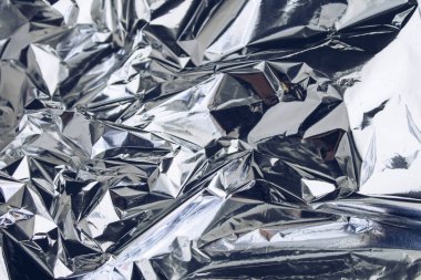 Buruşmuş folyo dokusu. Buruşuk kağıt renkli bir renkle parlar. Renkli yansımalı folyo.