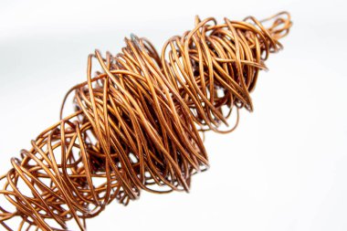 Bakır tel. Kablo bobini sarılmış. Kırmızı bakır kablo buruşmuş. Beyaz arkaplanda yakın plan.