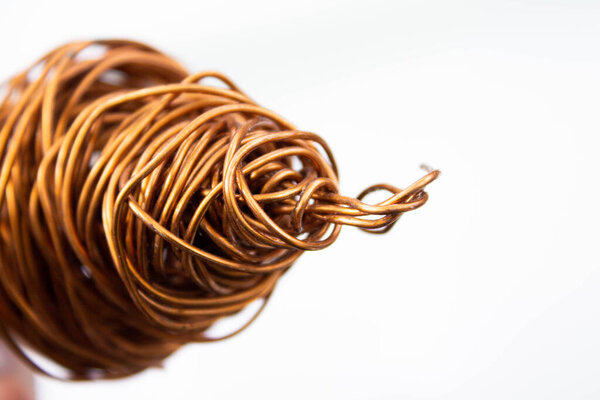 Copper wire . The wire coil is rolled up. The red copper wire is crumpled. Close-up on a white background.