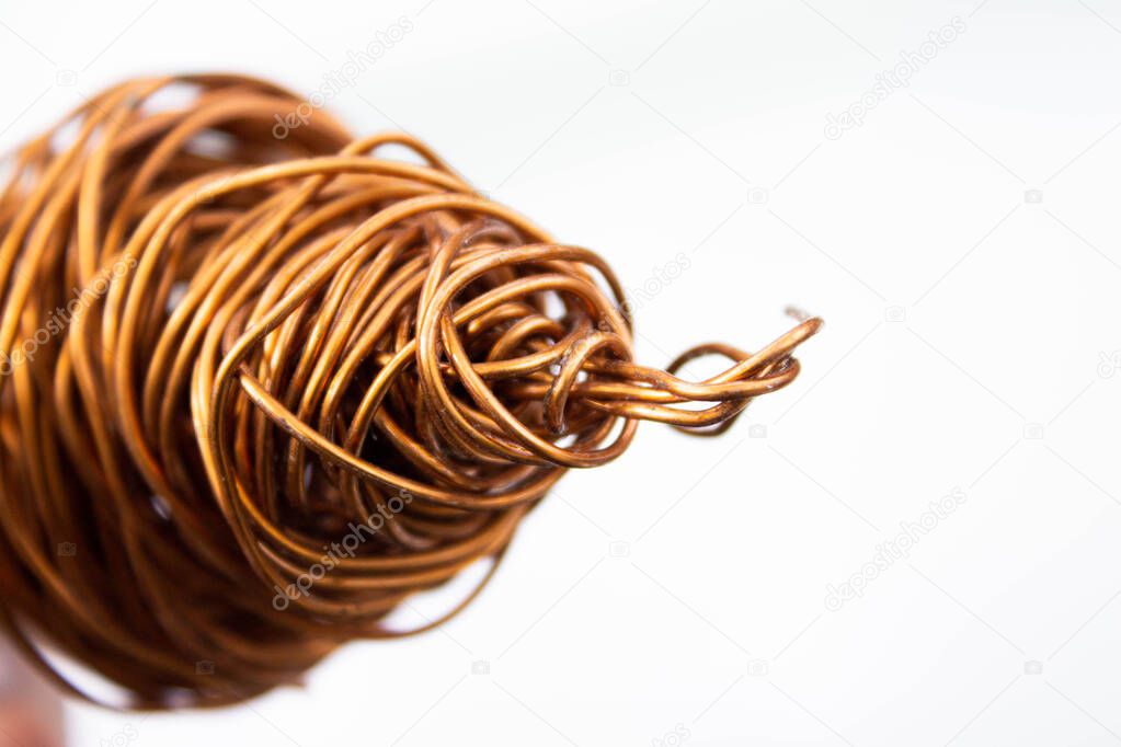 Copper wire . The wire coil is rolled up. The red copper wire is crumpled. Close-up on a white background.