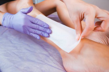 Balmumu tüyü. Balmumu şeritli epilasyon. Bacaklarda saç kesimi. Eldivenli el ve balmumu şerit.