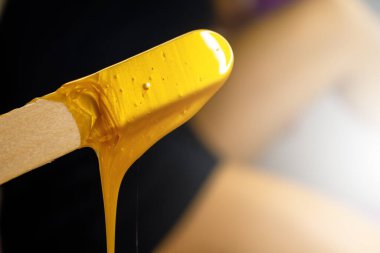 Erimiş tüy dökücü mum. Sıcak balmumuyla karıştırmak. Balmumu spatuladan akıyor. Balmumuyla tüy ayıklama. Kız saçlarını kesiyor..