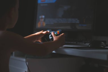 Çocuk bir bilgisayar oyunu oynuyor. Joystick elinde. Bilgisayar kulübünde bir oyuncu. Çocuk Oyunları.