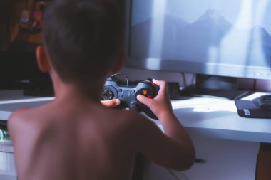 Çocuk bir bilgisayar oyunu oynuyor. Joystick elinde. Bilgisayar kulübünde bir oyuncu. Çocuk Oyunları.