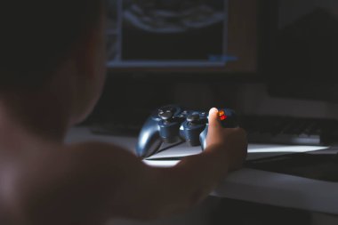 Çocuk bir bilgisayar oyunu oynuyor. Joystick elinde. Bilgisayar kulübünde bir oyuncu. Çocuk Oyunları.