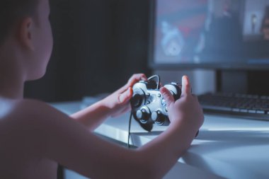 Çocuk bir bilgisayar oyunu oynuyor. Joystick elinde. Bilgisayar kulübünde bir oyuncu. Çocuk Oyunları.