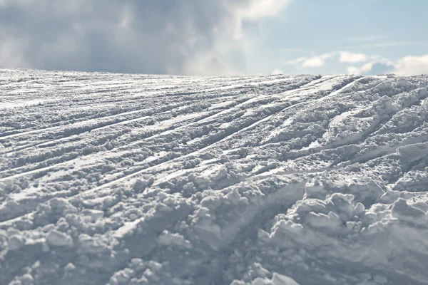 Uma seção de neve pingada, mostrando pistas de esqui correndo pela pista . — Fotografia de Stock