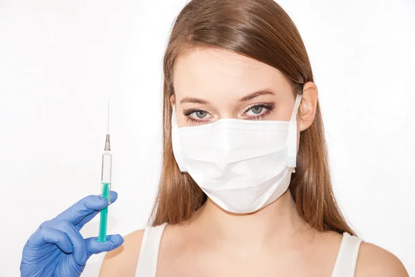 Bir maske ve eldiven giyiyor ve bir şırınga tutarak genç güzel kadın
