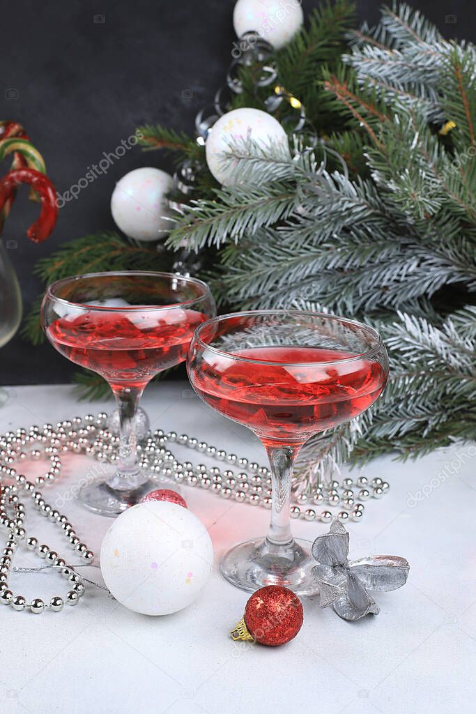 Pink alcoholic cocktail with lemonade, champagne or martini in glasses on a festive christmas table with fir branches and decorations, bar concept, spirits at a party, selective focus