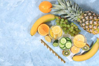 Detoks diyeti ve kilo verme konsepti. Meyve suyu ve malzemeler, mavi bir masada tropikal meyve ve kokteyller, üst görünüm, sağlıklı ve doğal yiyecek, C vitamini kaynağı, seçici odaklanma.,