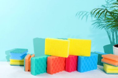 Bulaşık yıkamak için renkli süngerler ve arka planda köpükle temizlik. Evdeki temizlik kavramı, mikroplardan ve virüslerden korunma, seçici odaklanma.