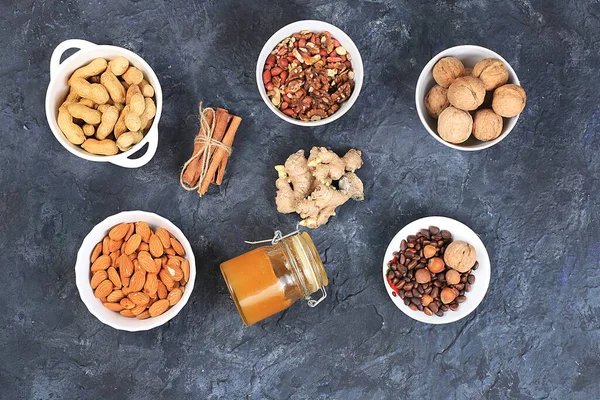 Assortment of different nuts, healthy natural food concept, almonds, pecans, pistachios, cashews, walnuts and pine nuts, honey, cinnamon, high calorie food with vegetable protein and vitamins