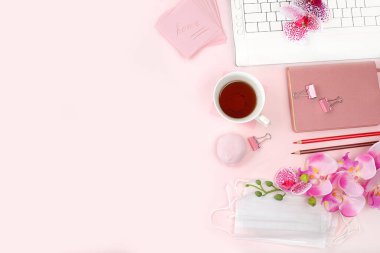 Bilgisayar, ışık masasında bir fincan çay ve bahar çiçeği, uzaktan kumanda, minimum iş konsepti. Modern kadınların masası. Coronavirüs salgını olan merkez ofis, evde kal, kendini koru, seçici odaklan.