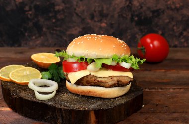 Taze marul yapraklı çizburger, domates, krem peynir, soğan ve pirzola eski ahşap bir tahtanın üzerinde, yemek teslimatı, kafe reklamı, restoran, menü, seçici odaklanma.