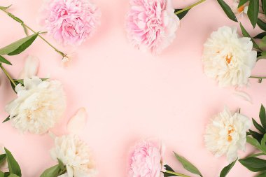 Pembe bir masanın üzerindeki şakayık çiçeklerinden yapılmış çerçeve, soyut çiçek kompozisyonu düz zemin, doğal zemin, anneler günü tebrik kartı, kadınlar günü, doğum günü, düğün, mesaj, seçici odak noktası