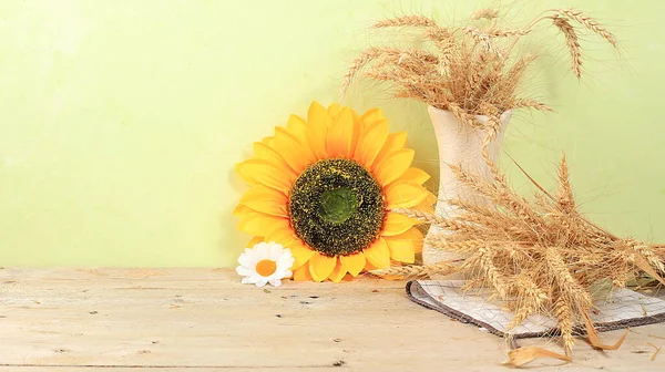 Thanksgiving background, harvest concept, autumn composition with sunflower flowers and ears of wheat and rye on a light background, rustic style, selective focus, place for text