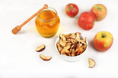 Beyaz arka planda elmalı ve ballı ev yapımı elma cipsleri, sonbahar elmaları kışın depolanmak için fırında veya kurutucuda pişirilir, lezzetli sağlıklı diyet yemekleri, elmalar kilo vermeyi teşvik eder.