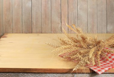 Eski arkaplanda yazı, köy tarzı, fırın ve hasat konsepti için yeri olan bir deste buğday olan boş ahşap masa, ürün sergisi için tasarım ve vitrin için makara yapın.,