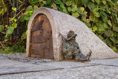Dwarf guards the entrance of a small building clipart