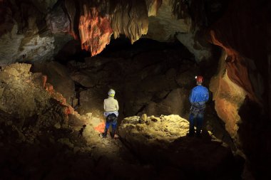 speleologists in lightened cave clipart