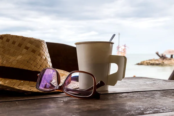 Carta tazza di caffè sul tavolo in legno in riva al mare — Foto Stock