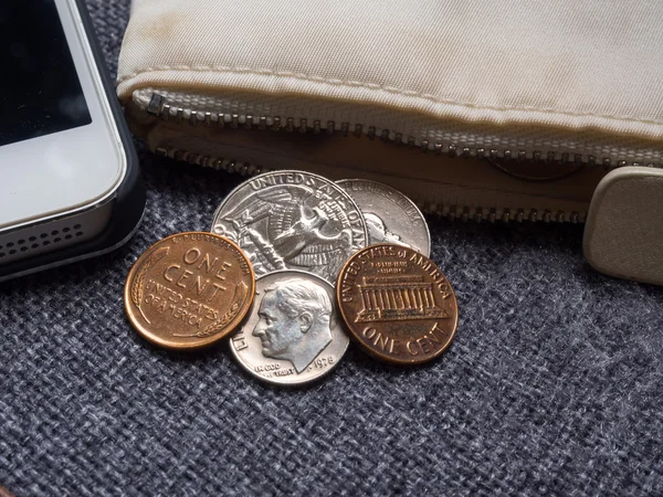 Monedas en dólares estadounidenses colocadas fuera de la billetera con smartphone . —  Fotos de Stock