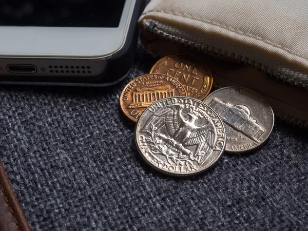 Monedas en dólares estadounidenses colocadas fuera de la billetera con smartphone . —  Fotos de Stock